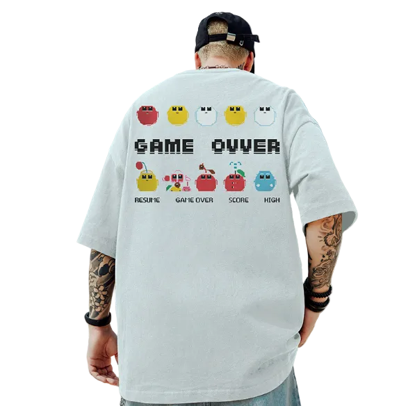 Person wearing a white t-shirt with a retro game design on the back, standing against a blue sky and rocky landscape.