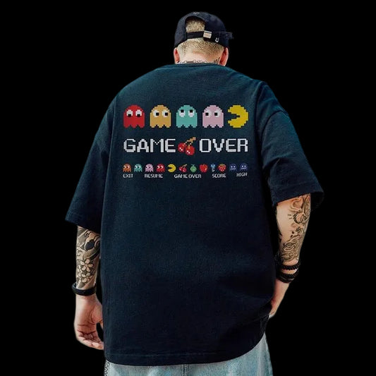 Person wearing a black t-shirt with 'GAME OVER' and Pac-Man graphics, standing against a cloudy sky.
