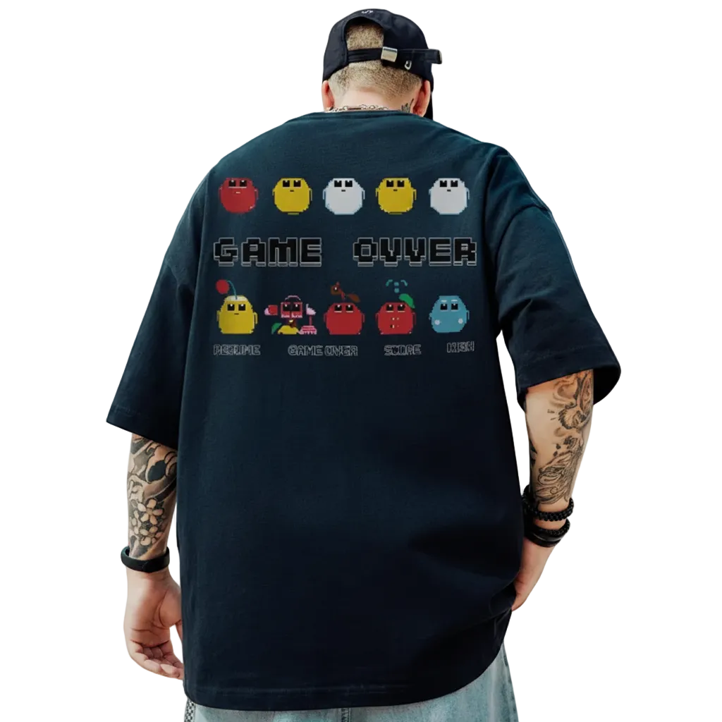 Person wearing a black t-shirt with a retro game design, standing outdoors with a blue sky and clouds in the background.