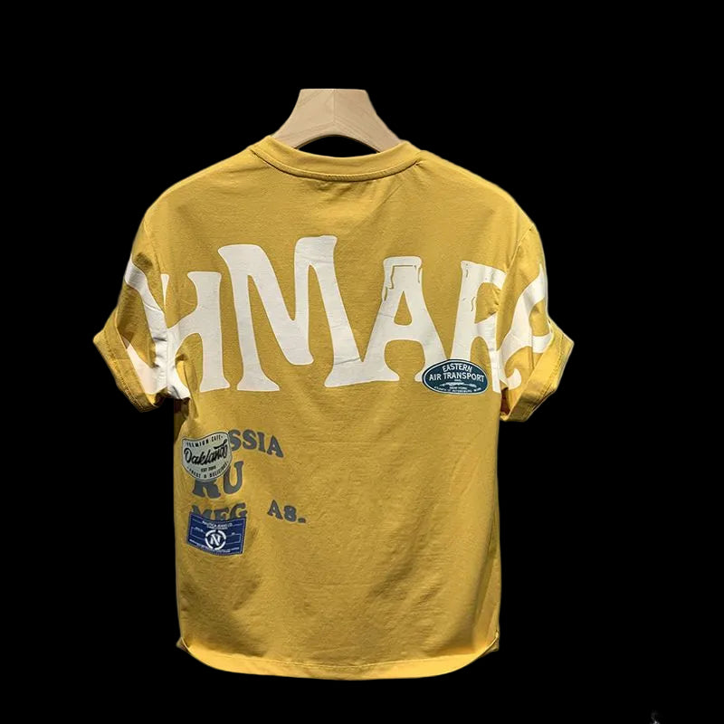 Yellow t-shirt with text and patches on a wooden hanger against a gray background